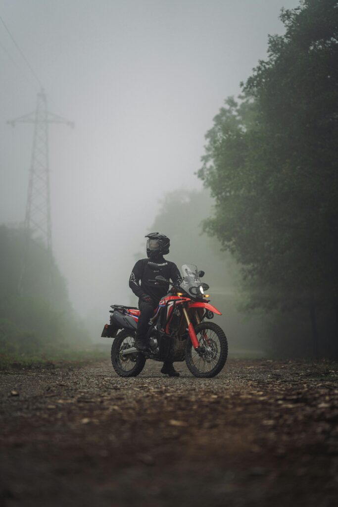 pexels-photo-32266158-32266158 Motorcycle rider in a foggy, forested area, exuding adventure and exploration.